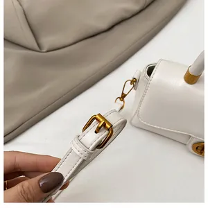 Détail d'un mini sac blanc carré avec boucle en métal doré et bandoulière réglable