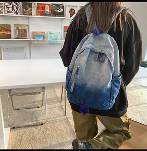 Détail du sac à dos en jean dégradé avec bords effilochés et sangles violettes