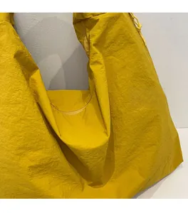 Close-up of bright yellow tote bag showing soft crinkled texture and lightweight nylon fabric