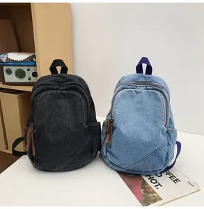 Detail view of vintage denim backpacks in black and light blue with zipper side pockets