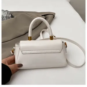 Détail de la texture du similicuir crème et des finitions métalliques dorées du sac carré