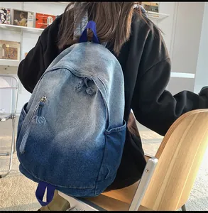 Détail du sac à dos en denim dégradé bleu avec fermeture éclair à franges et texture latérale