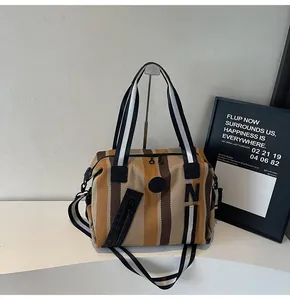 Detail of striped woven crossbody bag with dual zipper and adjustable shoulder strap