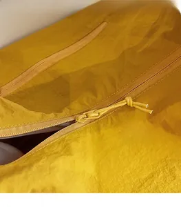 Detail showing high-quality smooth zipper with woven yellow rope puller on tote bag