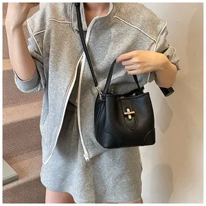 Detail of black lychee grain leather bucket bag with gold twist lock and shoulder strap