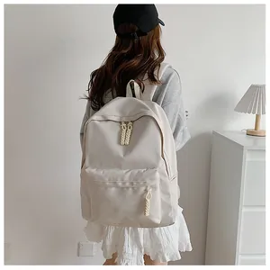 Rear view of model wearing a minimalist cream nylon backpack with woven zip detail