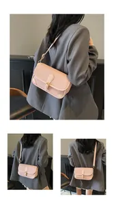 Détail du sac bandoulière rose clair avec motif litchi, boucle dorée et sangle réglable