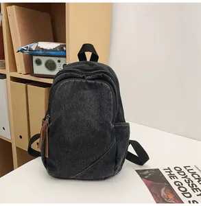 Detail of a vintage washed denim backpack featuring diagonal stitching and leather zip pulls