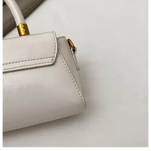 Détail d'un sac à main en cuir crème avec finitions dorées et coutures de haute précision