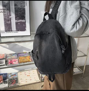 Détail d'un sac à dos en jean délavé gris avec zip à franges et larges bandoulières