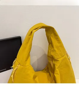 Close-up of durable shoulder strap and pleated texture on a yellow nylon tote bag