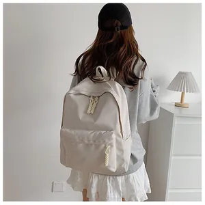 Detail view of a minimalist beige student backpack with unique woven rope zipper pulls