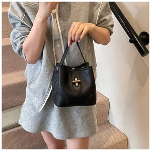 Detail of black pebbled leather bucket bag with a classic golden twist lock closure