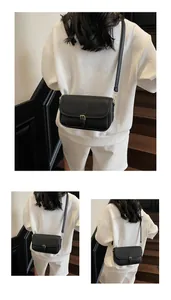 Détail d'un sac bandoulière noir texture litchi avec boucle métallique et ferrures dorées
