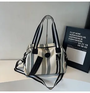 Detail of striped tote bag showing front zipper pocket and bold black letter N patch