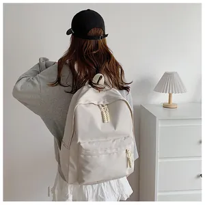 Detail view of a large cream-white nylon backpack with adjustable straps and woven zippers