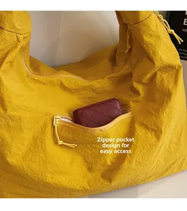 Detail of the side zipper pocket on a crinkled yellow tote bag for easy storage