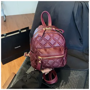 Detail of burgundy quilted mini backpack with gold zippers and glossy leather finish