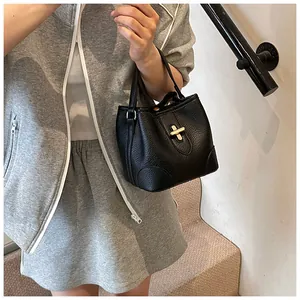 Detail of black pebbled leather bucket bag with gold metal lock and single handle