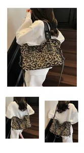 Leopard print tote bag with black leather handles and shoulder strap in a stylish setting