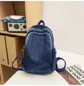 Detailed view of dark blue washed denim backpack with brown leather zipper pulls