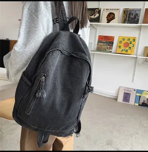 Détail du sac à dos en jean gris foncé avec texture délavée et fermeture éclair à glands
