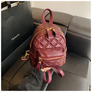 Detail view of burgundy quilted mini backpack with golden zippers on a black seat