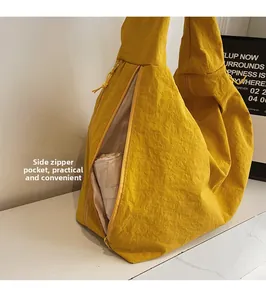 Detail of the side zipper pocket on a yellow nylon tote bag storing a folding umbrella