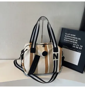 Macro shot of striped canvas tote with black double handles and durable zipper detail