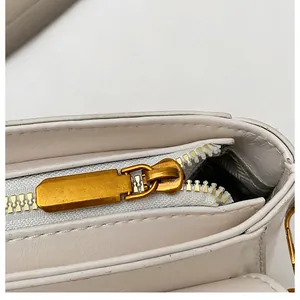 Détail du zip métallique doré et des coutures sur un sac bandoulière en cuir ivoire