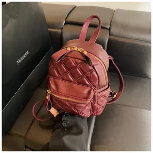 Detailed macro view of wine red quilted leather backpack with gold zipper hardware