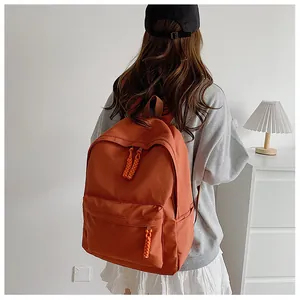 Detail of caramel backpack with woven zipper pulls and side pockets on model