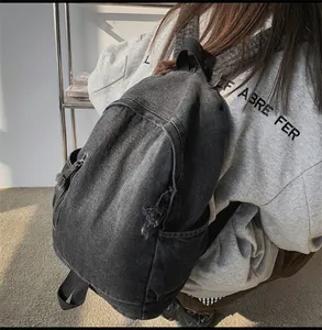 Vue détaillée d'un sac à dos en denim gris foncé avec poches latérales et rubans zippés