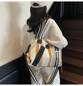 Detail showing high-capacity striped canvas tote bag with contrast woven shoulder strap