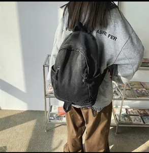 Détail du sac à dos en denim noir délavé avec grand compartiment principal et style rétro