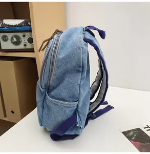 Side view of denim backpack showing side pocket and purple straps in home setting