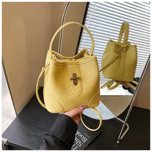 Detail of a bright yellow bucket bag showing lychee grain leather and gold metal twist lock