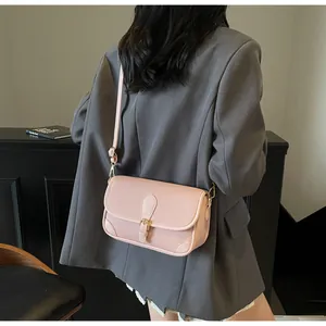 Sac bandoulière en cuir texturé rose avec détails dorés porté à l'épaule sur un mannequin