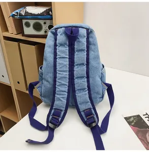 Detail view of denim backpack back with purple nylon straps and adjustable buckles