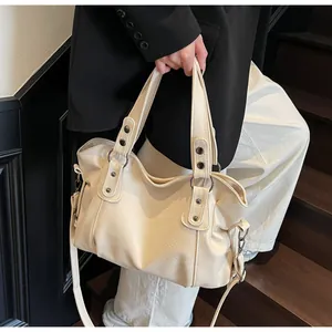 Macro shot of cream lychee-textured leather bag with vintage metal rivets and dual handles