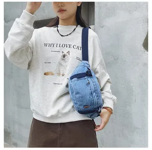 Detailansicht der blauen Denim-Brusttasche mit Metallreißverschluss und Tragegurt