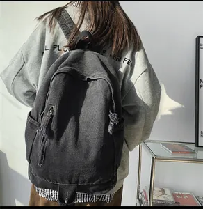 Détail du tissu denim noir délavé et de la poche frontale zippée du sac à dos