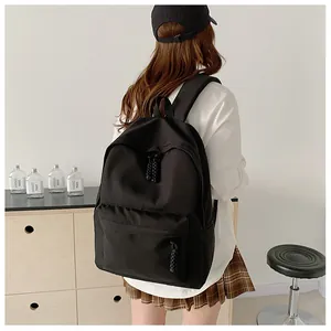 Side view of a student carrying a black canvas backpack with woven zipper pulls