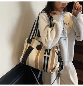 Lifestyle shot of large striped canvas tote bag with adjustable black shoulder strap