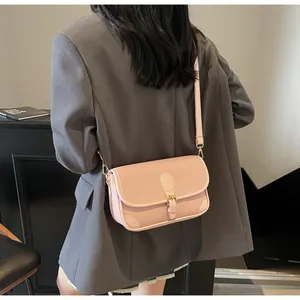 Gros plan d'un sac bandoulière en cuir rose à texture litchi avec boucle métallique