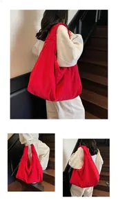 Detail of red large capacity tote bag featuring wrinkled texture and wide shoulder strap