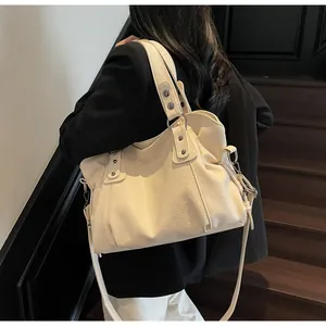 Large beige faux leather tote bag with wide shoulder straps shown on a model