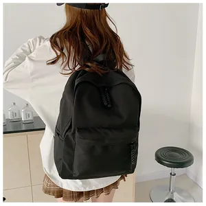 Rear view of a black minimalist canvas backpack worn by a model in a modern room