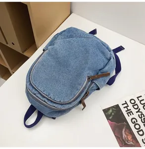 Detailed macro of vintage denim backpack with brown leather zipper pull and front pocket