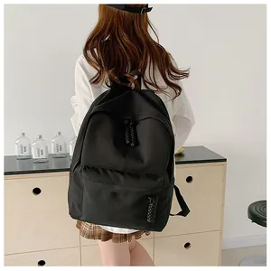 Detail of minimalist black canvas backpack showing the zipper with woven cord decoration